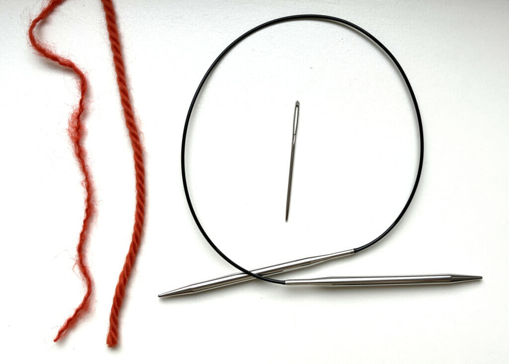 Du benötigst drei Wollknäuel, eine Rundstricknadel und eine Wollnadel, um die Mütze zu stricken.