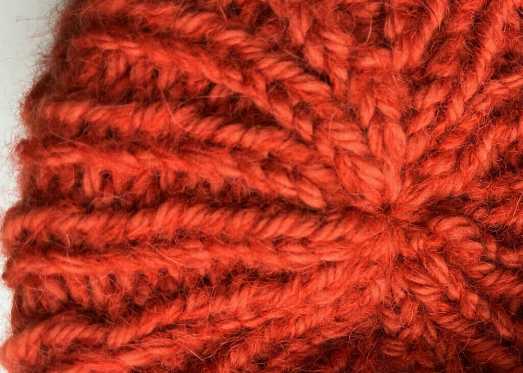 Mit dem Vernähen des Fadens wurde die gestrickte Mütze oben auf dem Kopf nun erfolgreich geschlossen.